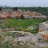 Da questo punto in poi non si potrebbe proseguire, ma decidiamo comunque di avventurarci in avanti costeggiando un alto muro di cinta e inoltrandoci nella campagna. Solo in questo modo riusciamo ad ammirare dall�alto le rosse pareti rocciose di una delle due cave di pietra in disuso dove sono state rintracciate le orme di dinosauro (foto di Nicola Imperiale)